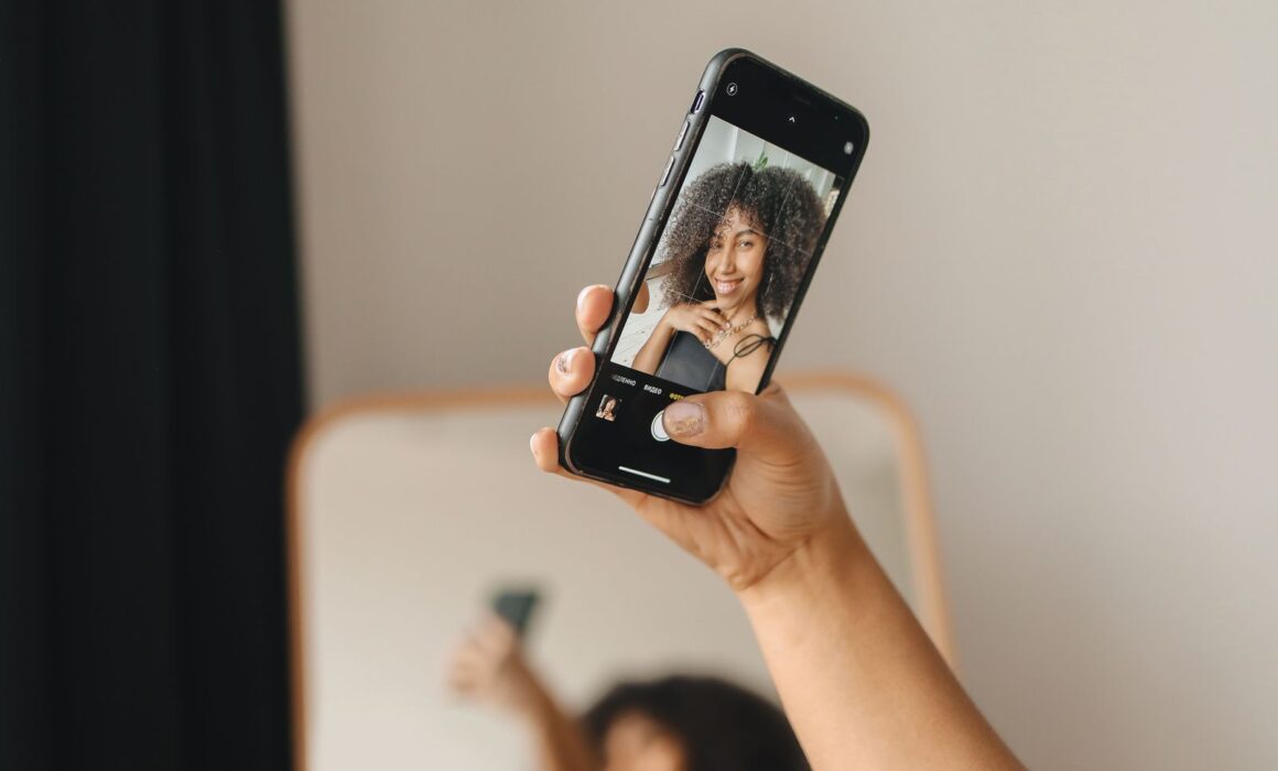 Hand hält ein Smartphone mit Selfie-Porträt – typischer Fehler beim selbstgemachten Bewerbungsfoto